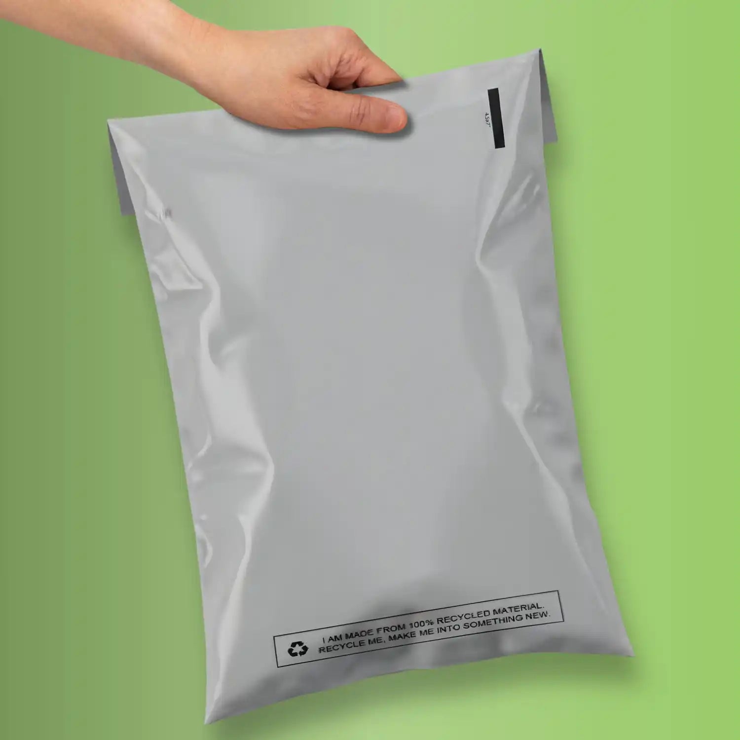 100% grey mailing bag being held on a green background