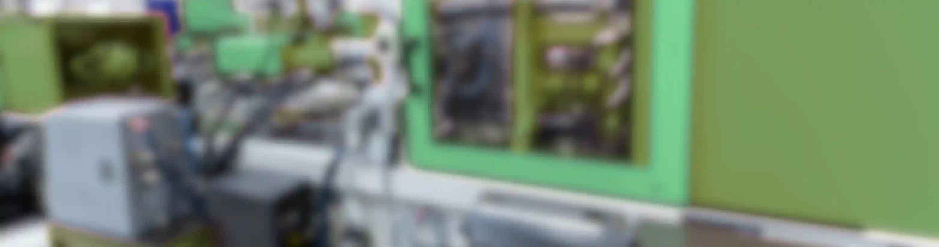Blurred image of green machinery inside of factory